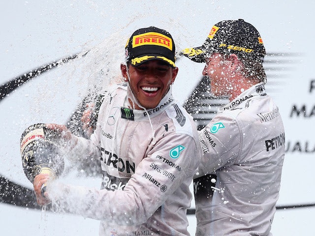 Lewis Hamilton of Great Britain and Mercedes GP (L) celebrates on the podium with second placed Nico Rosberg of Germany and Mercedes GP after the Malaysian Grand Prix on March 30, 2014