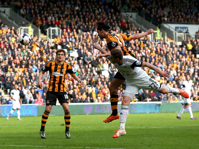 George Boyd of Hull City rises above Angel Rangel of Swansea to score the opening goal with a header during the Barclays Premier league match between Hull City and Swansea City at KC Stadium on April 5, 2014
