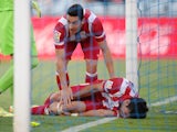 Koke of Club Atletico de Madrid conforts teammate Diego Costa after Costa knocked his knee off the goalposts while scoring Atletico's 2nd goal against Getafe on April 13, 2014