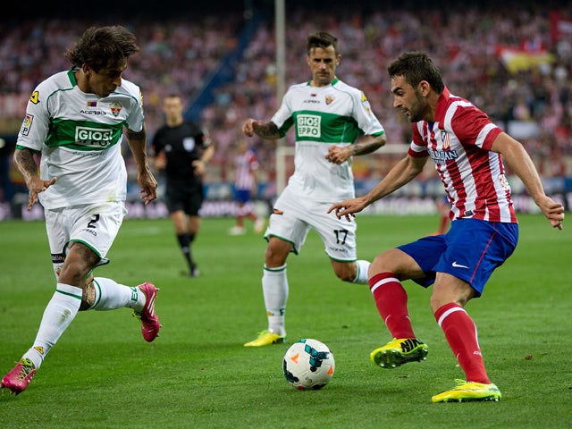 Adrian Lopez of Atletico de Madrid competes for the ball with Damian Suarez of Elche FC and his teammate Javier Marquez Moreno during the La Liga match between Club Atletico de Madrid and Elche FC at Vicente Calderon Stadium on April 18, 2014