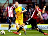 Keith Keane of Preston skips past the challenge of Marcelo Trotta of Brentford during the Sky Bet League One match between Brentford and Preston North End at Griffin Park on April 18, 2014 