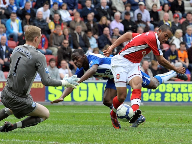 Arsenal's English forward Theo Walcott (R) scores the opening goal past Wigan Athletic's English goalkeeper Chris Kirkland (L) during the English Premier league football match on April 18, 2010