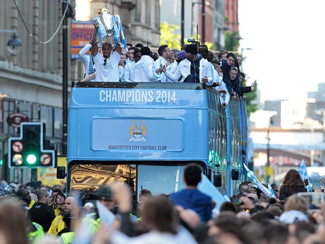 Manchester City's Belgian defender Vincent Kompany holds up the Premiership trophy as the club's players celebrate during a victory parade on an open-topped bus through the streets of Manchester, northwest England, on May 12, 2014