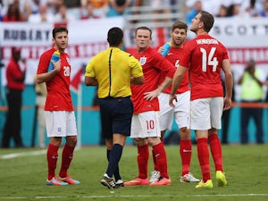 Wayne Rooney of England (C) speaks to referee Ricardo Salazar as Adam Lallana (L), Steven Gerrard (2nd R) and Jordan Henderson (R) look on as Salazar delays the match due to a storm on June 7, 2014