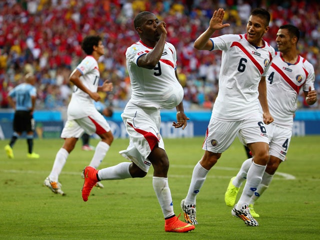 Joel Campbell of Costa Rica celebrates scoring his team's first goal with the ball under his jersey as teammates Oscar Duarte and Michael Umana run on during the 2014 FIFA World Cup Brazil Group D match between Uruguay and Costa Rica at Castelao on June 1