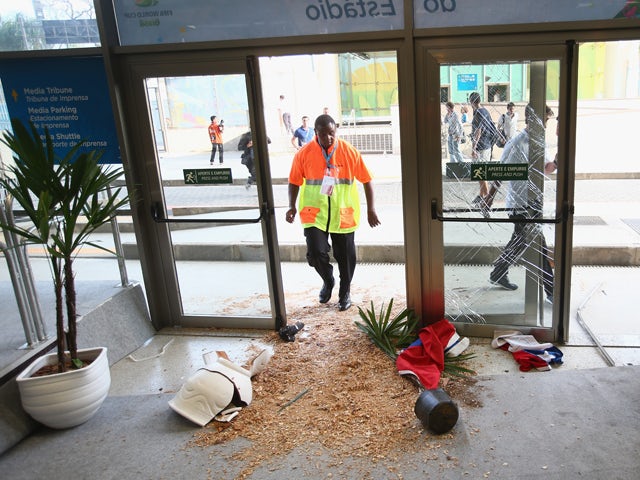 Security personnel stand near broken doors and planters after fans broke through security entering the stadium prior to the 2014 FIFA World Cup Brazil Group B match between Spain and Chile at Maracana on June 18, 2014