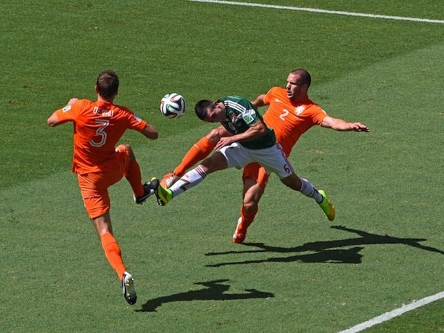 Hector Herrera of Mexico goes for a header against Stefan de Vrij (L) and Ron Vlaar of the Netherlands during the 2014 FIFA World Cup round of 16 match in Fortaleza on June 29, 2014