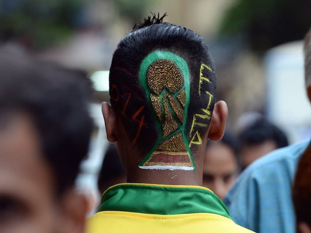 India football enthusiast Nilesh Kadam sports a FIFA World Cup trophy logo painted into a haircut as he walks along a street after visiting a salon in Mumbai on June 9, 2014