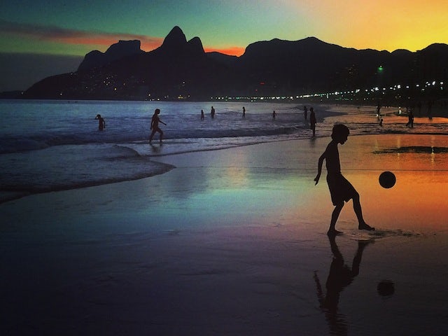 A young boy plays football at sunset on June 8, 2014 in Rio de Janeiro, Brazi