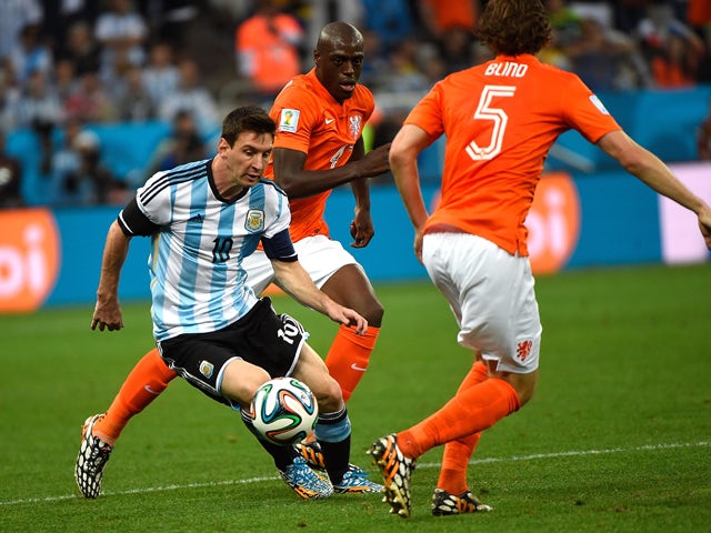 Netherlands' defender Bruno Martins Indi watches as Argentina's forward and captain Lionel Messi controls the ball past Netherlands' defender Daley Blind during the 2014 FIFA World Cup Brazil Semi Final match between the Netherlands and Argentina at Arena