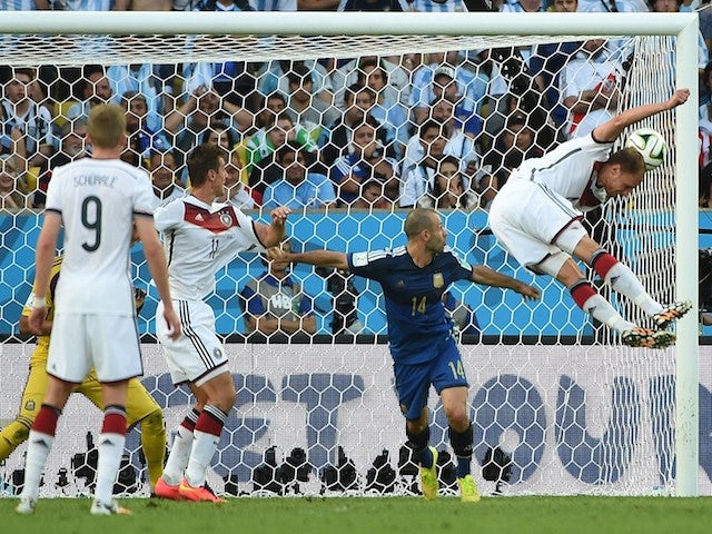 Germany's defender Benedikt Hoewedes (R) heads the ball towards the goal as Argentina's midfielder Javier Mascherano (C) and Germany's forward Miroslav Klose watch on during the World Cup final on July 13, 2014 