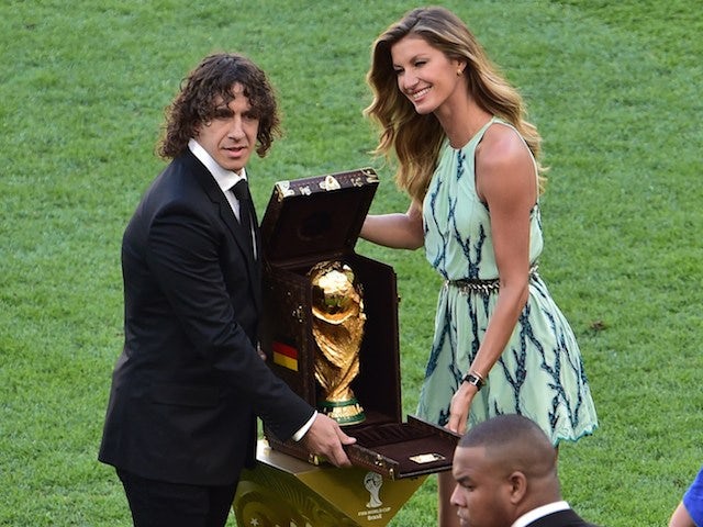 Spanish defender Carles Puyol (L) poses with the World Cup (C) and Brazilian model Gisele Bundchen (R) during a closing ceremony ahead of the final football match on July 13, 2014
