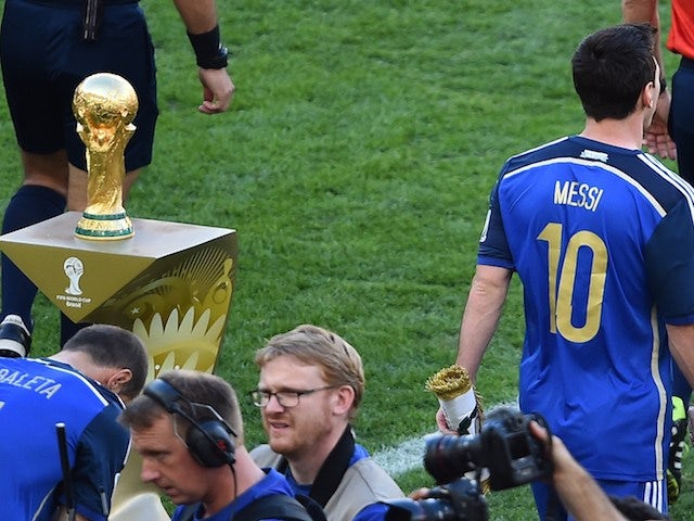 Argentina's forward and captain Lionel Messi (R) walks past the World Cup ahead of the final football match between Germany and Argentina on July 13, 2014