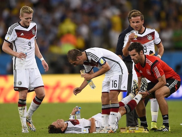 Germany's forward Andre Schuerrle (L) and Germany's defender and captain Philipp Lahm (C) speak with Germany's midfielder Mesut Ozil (bottom) as hereceives medical treatment on July 13, 2014