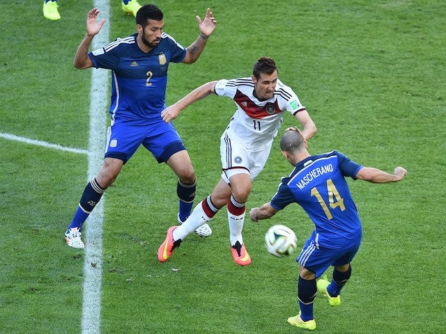Germany's forward Miroslav Klose (C) tackles Argentina's midfielder Javier Mascherano (R) as Argentina's defender Ezequiel Garay looks on during the final football match on July 13, 2014