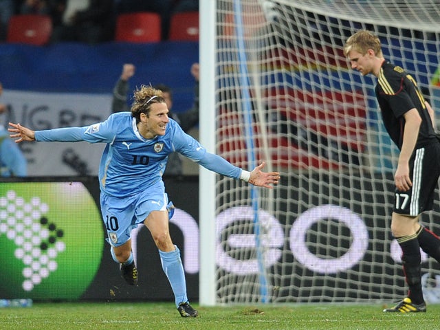 Uruguay's striker Diego Forlan celebrates after scoring as Germany's defender Per Mertesacker dejects during the 2010 World Cup third place match Uruguay vs Germany on July 10, 2010