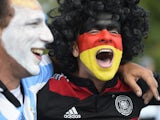 An Argentina and Germany fan with their faces painted in the national colors cheer prior to the 2014 FIFA World Cup final football match between Germany and Argentina at the Maracana Stadium in Rio de Janeiro on July 13, 2014