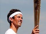 Badminton player Nathan Robertson of England poses with the torch during the hand-over of the Olympic Torch at Wembley Stadium on July 25, 2012