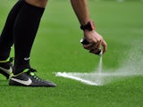 Referee Mike Dean uses vanishing spray to mark the pitch for a free kick during the English Premier League football match between Manchester United and Swansea City at Old Trafford in Manchester, north west England on August 16, 2014