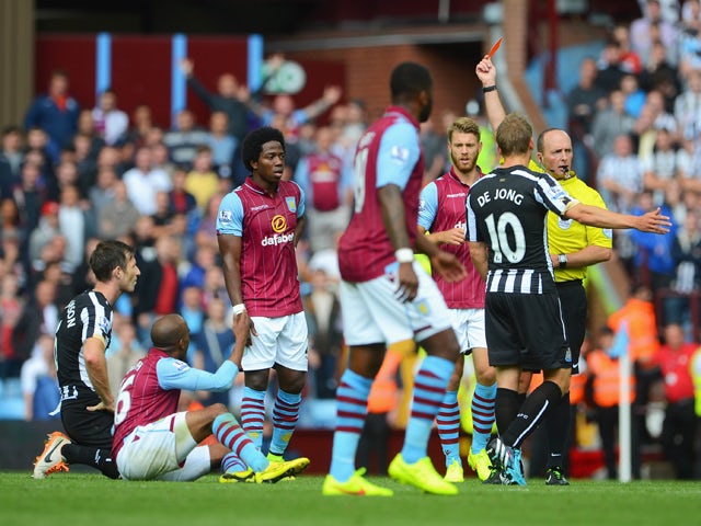  Referee Mike Dean shows the red card to Mike Williamson of Newcastle United during the Barclays Premier League match between Aston Villa and Newcastle United at Villa Park on August 23, 2014