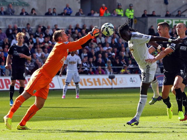 Burnley's English goalkeeper Tom Heaton makes a save from Swansea City's French striker Bafetimbi Gomis during the English Premier League football match between Swansea City and Burnley at the Liberty Stadium in Swansea on August 23, 2014