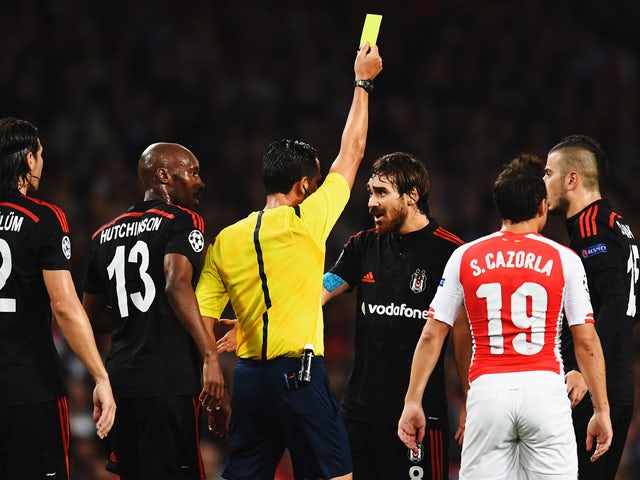 Veli Kavlak of Besiktas is shown the yellow card by match referee Pedro Proenca during the UEFA Champions League Qualifier 2nd leg match between Arsenal and Besiktas at the Emirates Stadium on August 27, 2014