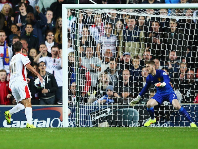 Will Grigg of Milton Keynes Dons scores his second goal past goalkeeper David De Gea of Manchester United during the Capital One Cup Second Round match on August 26, 2014