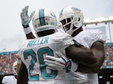 Lamar Miller #26 of the Miami Dolphins is congratulated by teammate Dion Sims #80 after Miller's first quarter touchdown catch during a game against the New England Patriots on September 7, 2014