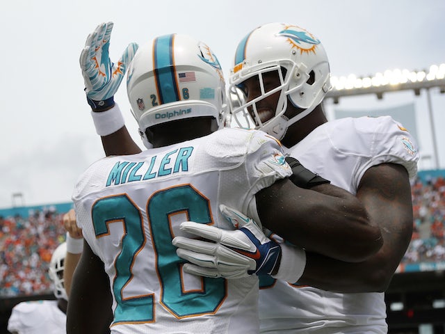 Lamar Miller #26 of the Miami Dolphins is congratulated by teammate Dion Sims #80 after Miller's first quarter touchdown catch during a game against the New England Patriots on September 7, 2014
