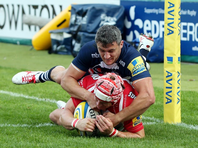 Rob Cook of Gloucester Rugby scores a try in the corner as Tom Brady of Sale Sharks tries to tackle during the Aviva Premiership match between Gloucester Rugby and Sales Sharks at Kingsholm on September 13, 2014