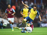 Santi Cazorla of Arsenal is challenged during the Barclays Premier League match between Aston Villa and Arsenal at Villa Park on September 20, 2014