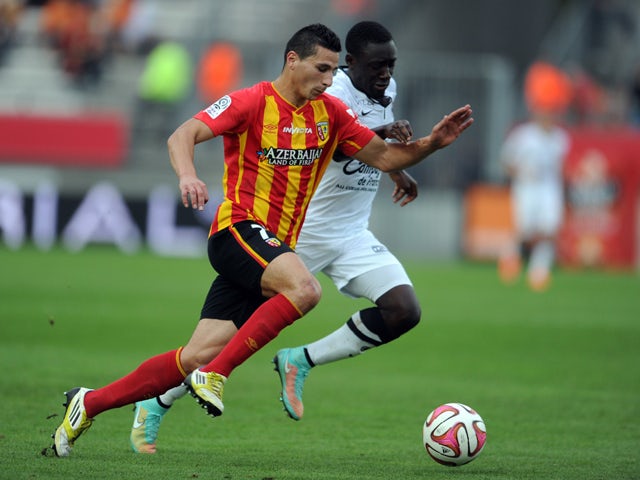 Lens French forward Yoann Touzghar vies with Caen's French defender Dennis Appiah during the French L1 football match Lens vs Caen on September 28, 2014