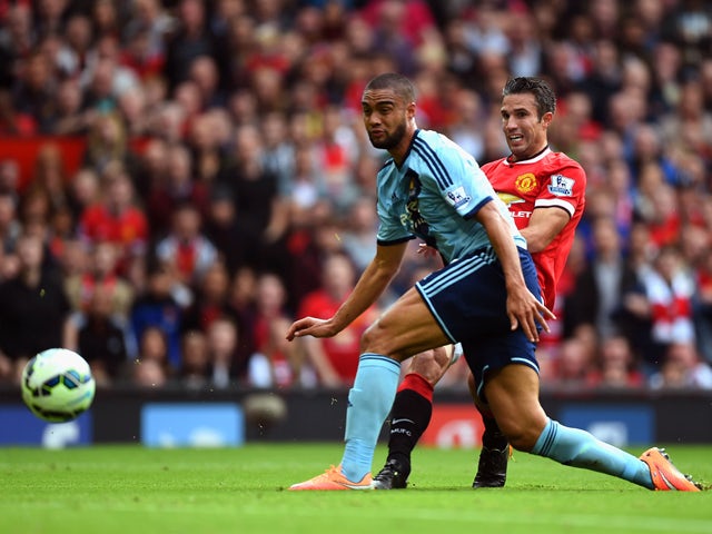 Robin van Persie of Manchester United shoots past Winston Reid of West Ham to score his team's second goal during the Barclays Premier League match between Manchester United and West Ham United at Old Trafford on September 27, 2014