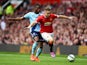 Luke Shaw of Manchester United goes past the challenge from Diafra Sakho of West Ham during the Barclays Premier League match between Manchester United and West Ham United at Old Trafford on September 27, 2014