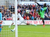 Papiss Demba Cisse of Newcastle United (R) scores their second past goalkeeper Lukasz Fabianski of Swansea City during the Barclays Premier League match between Swansea City and Newcastle United at Liberty Stadium on October 4, 2014