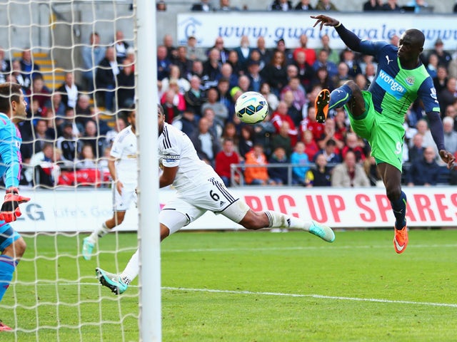 Papiss Demba Cisse of Newcastle United (R) scores their second past goalkeeper Lukasz Fabianski of Swansea City during the Barclays Premier League match between Swansea City and Newcastle United at Liberty Stadium on October 4, 2014
