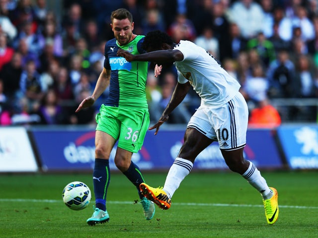 Wilfried Bony of Swansea City shoots past Paul Dummett of Newcastle United to score their first goal during the Barclays Premier League match between Swansea City and Newcastle United at Liberty Stadium on October 4, 2014