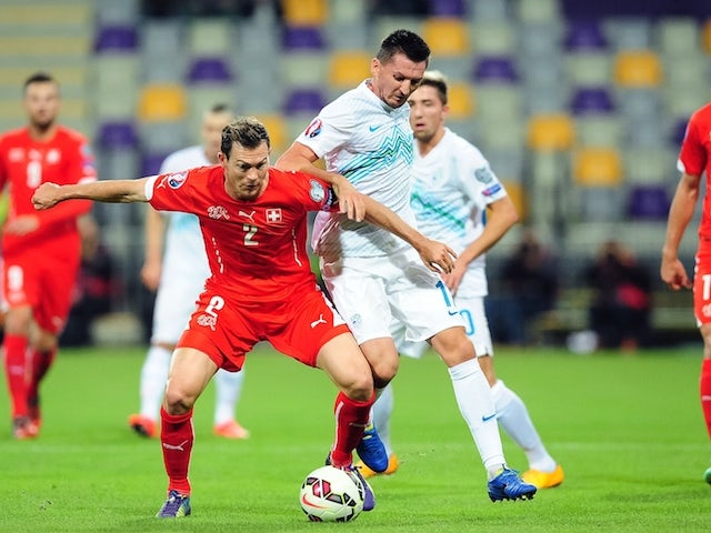 Switzerland's defender Stephan Lichtensteiner (L) vies for the ball with Slovenia's midfielder Andraz Kirm (2ndR) during the Euro 2016 qualifying match on October 9, 2014