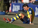 Arsenal's Mesut Ozil sits down off the pitch with an injury during the Premier League match against Leicester City on August 31, 2014