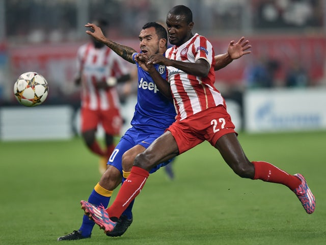Olympiacos' Eric Abidal fights for the ball with Juventus' Carlos Tevez during the Group A Champions League football match Olympiacos vs Juventus at the Karaiskaki stadium in Athens' Piraeus district on October 22, 2014