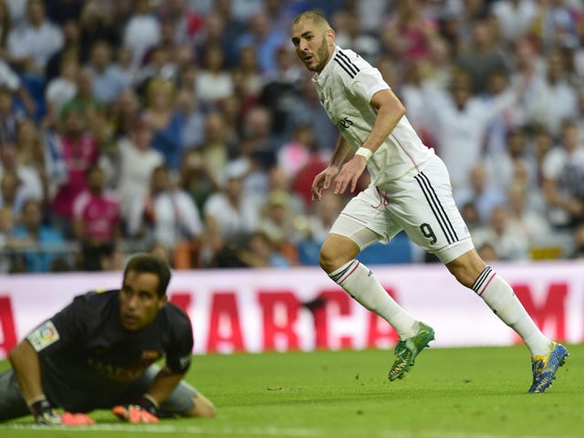 Real Madrid's French forward Karim Benzema looks to Barcelona's goalkeeper Claudio Bravo after scoring during the Spanish league football match Real Madrid CF vs FC Barcelona at the Santiago Bernabeu stadium in Madrid on October 25, 2014