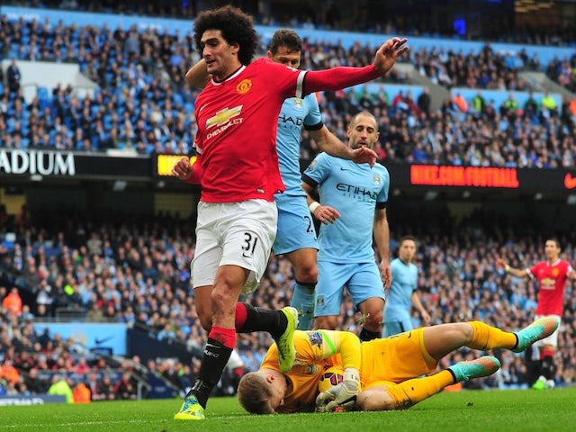 Manchester City's English goalkeeper Joe Hart (R) saves at the feet of Manchester United's Belgian midfielder Marouane Fellaini (L) during the English Premier League football match on November 2, 2014