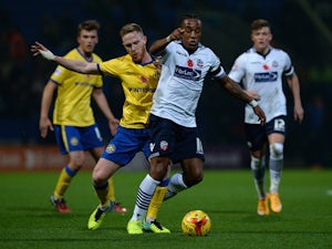 Neil Danns of Bolton Wanderers is tackled by Adam Forshaw of Wigan Athletic during the Sky Bet Championship match between Bolton Wanderers and Wigan Athletic at Macron Stadium on November 7, 2014