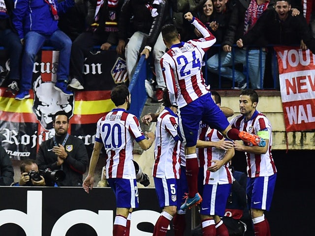 Atletico Madrid's players celebrate their first goal during the UEFA Champions League Group A football match Atletico Madrid vs Olympiakos FC at the Vicente Calderon stadium in Madrid November 26, 2014