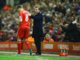 A fan applauds as Steven Gerrard of Liverpool prepares to come onto the pitch as a substitute alongside Brendan Rodgers manager of Liverpool during the Barclays Premier League match between Liverpool and Stoke City at Anfield on November 29, 2014