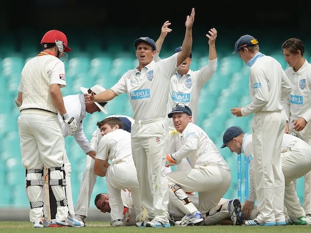 Phil Hughes lies on the ground surrounded by teammates after taking a knock to the head on November 25, 2014