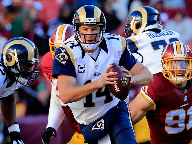 Quarterback Shaun Hill #14 of the St. Louis Rams scrambles to avoid the pressure of outside linebacker Ryan Kerrigan #91 of the Washington Redskins in the second quarter of a game at FedExField on December 7, 2014