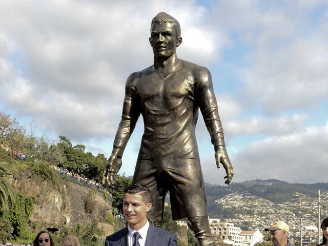 Portuguese football player Cristiano Ronaldo from the Real Madrid poses with his son beneath a statue of himself during the unveling ceremony in his hometown in Funchal on December 21, 2014