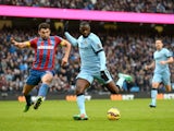 Manchester City's Ivorian midfielder Yaya Toure shoots to score their third goal as Crystal Palace's Australian midfielder Mile Jedinak closes in during the English Premier League football match between Manchester City and Crystal Palace at the Etihad Sta