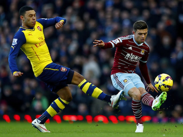 Aaron Cresswell of West Ham passes the ball under pressure from Alex Oxlade-Chamberlain of Arsenal during the Barclays Premier League match on December 28, 2014